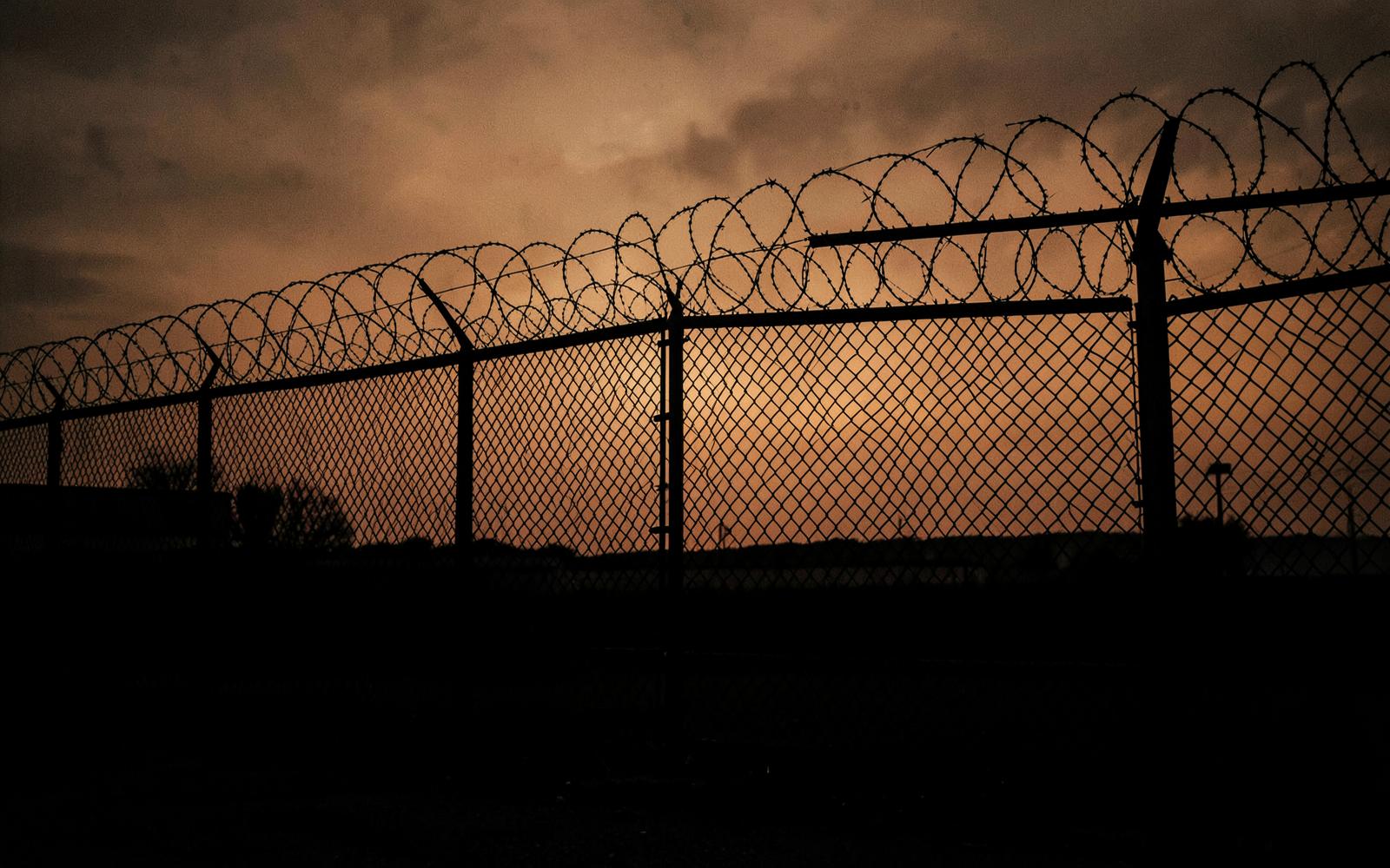 Barbed wire fence silhouetted against a dark orange Texas dusk